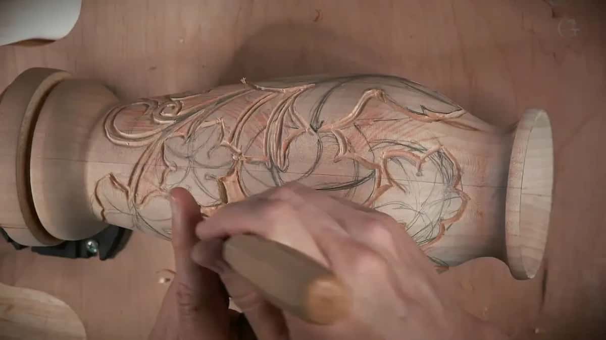 Two hands drive a gouge along the vase