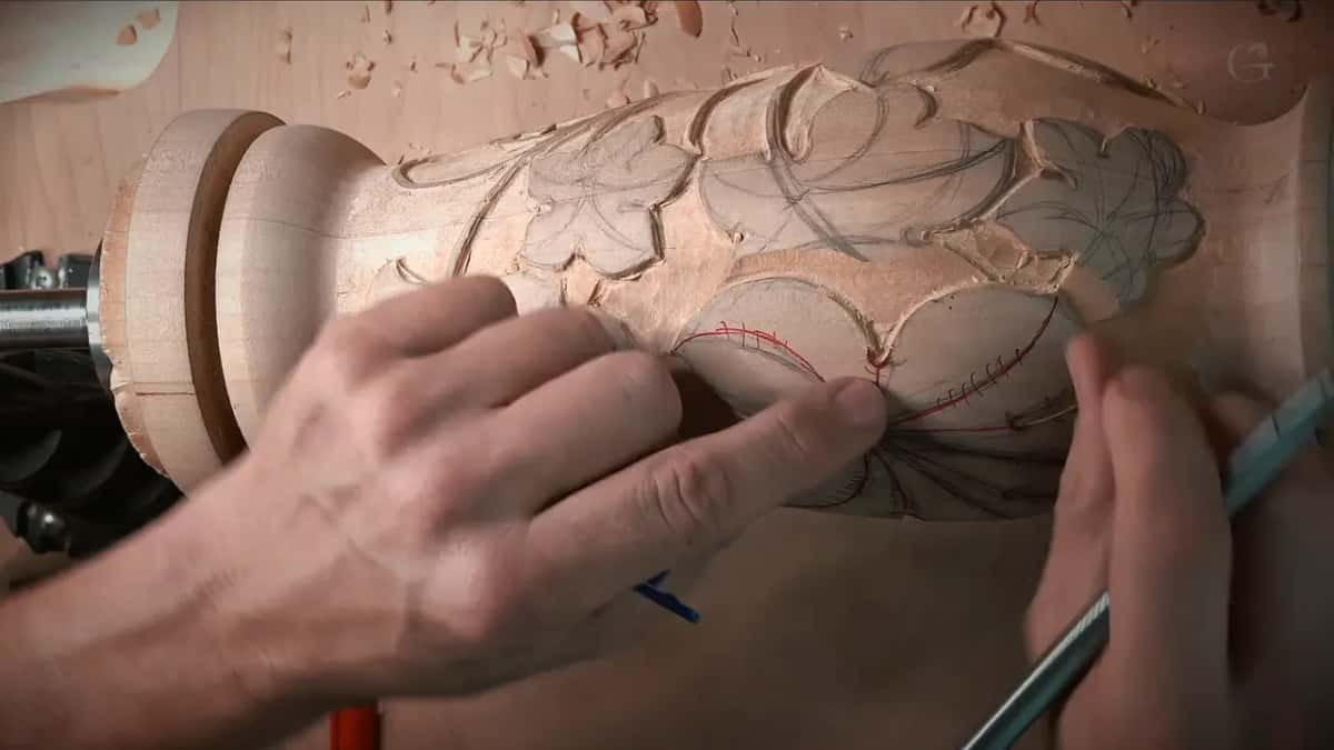 Left hand steadies the vase while the right draws red and blue lines onto one big leaf
